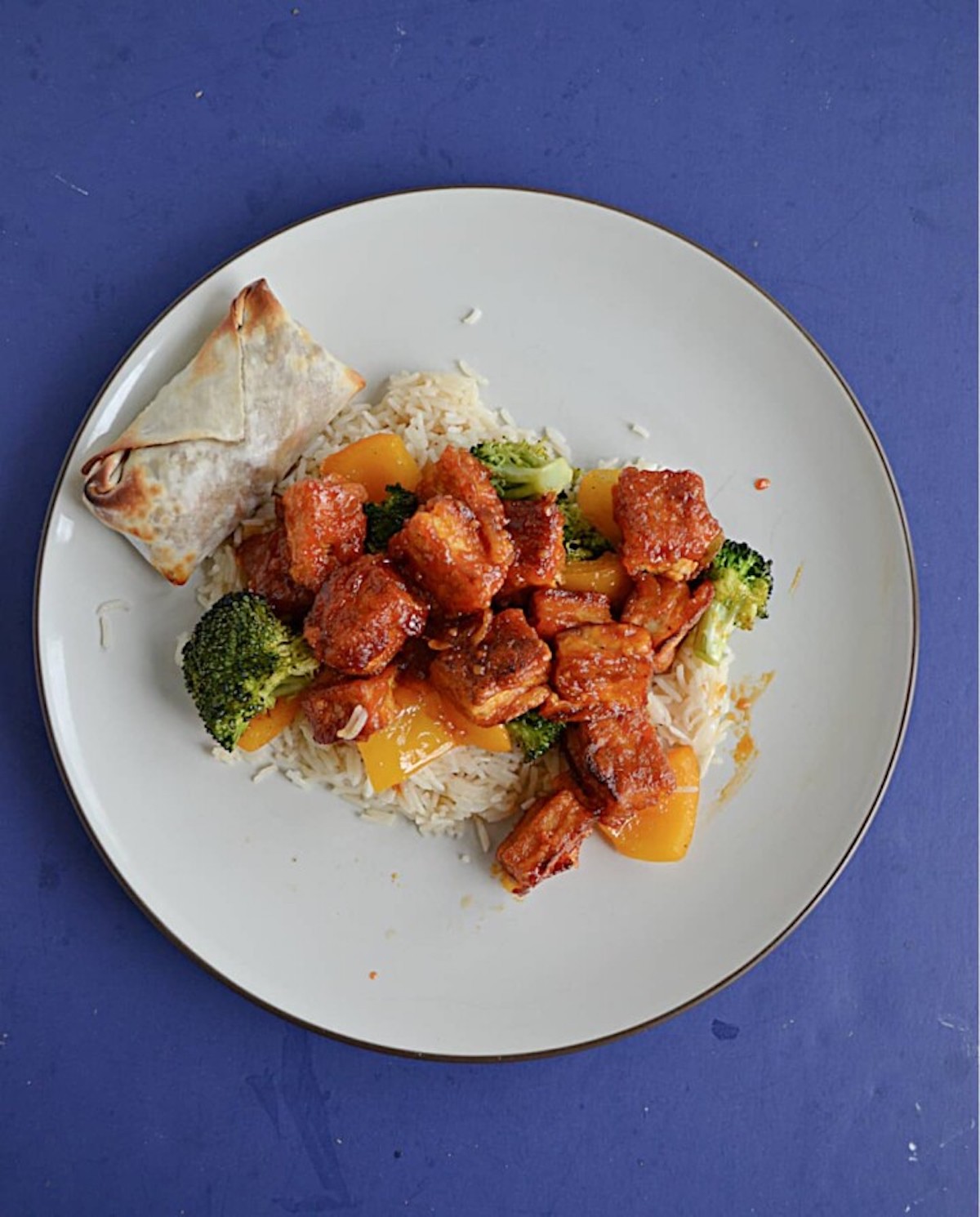 Firecracker tofu cubes on a white plate on a blue background.