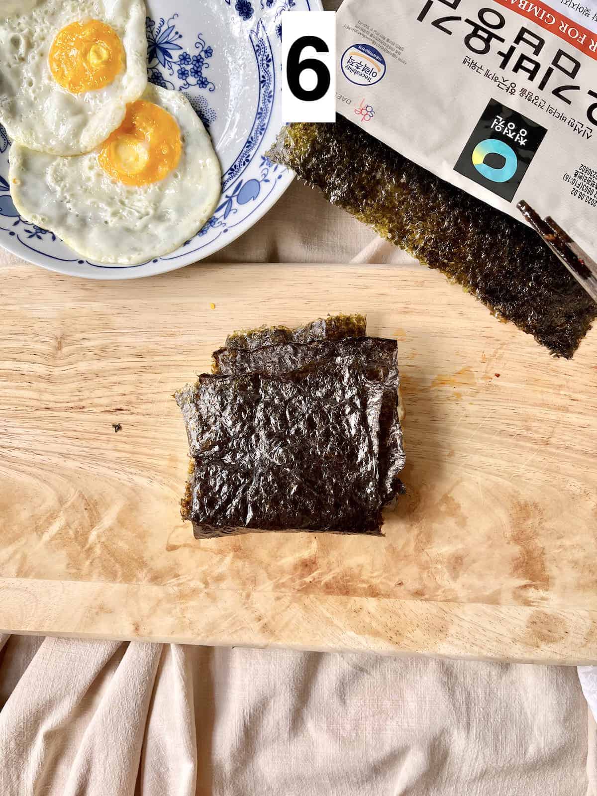 A folded Korean kimbap sandwich on a wooden cutting board.