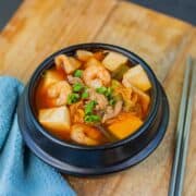 A photo of Korean Kimchi soup in a traditional Korean black soup bowl.