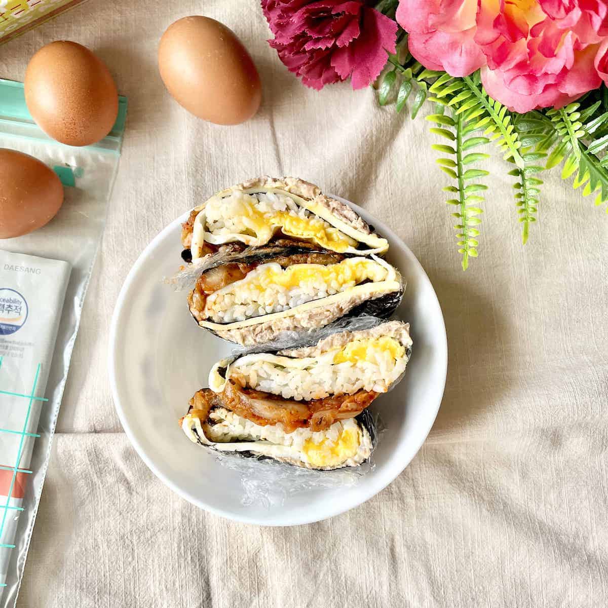 Folded kimbaps, stuffed with cheese, kimchi, tuna and egg, in a bowl.