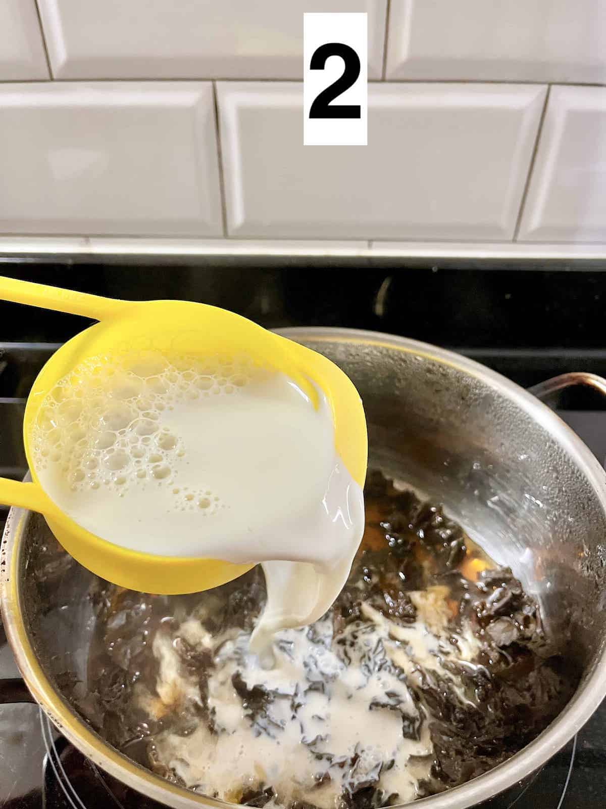 Pouring whole milk into a pot of boiling tea.