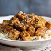 Close-up of tofu cubes smothered in sticky Asian sauce.