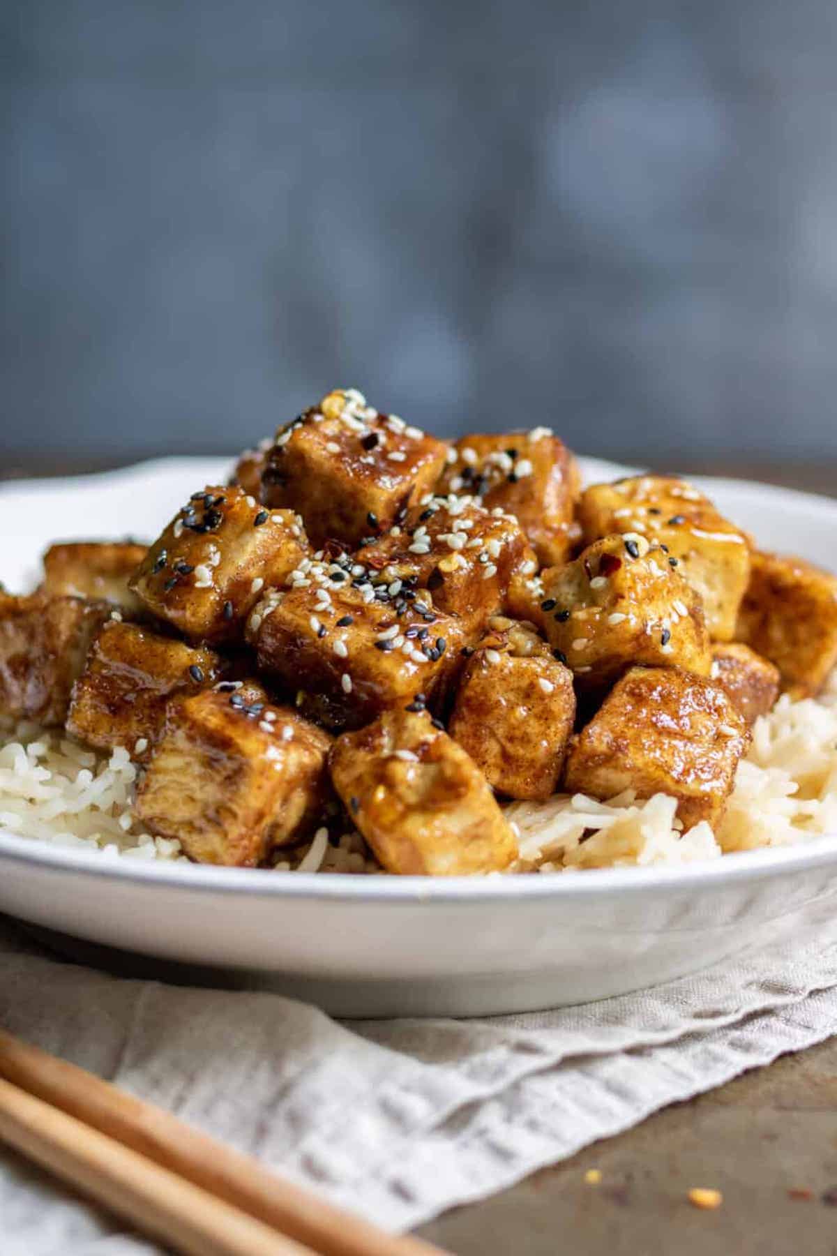 Close-up of tofu cubes smothered in sticky Asian sauce.