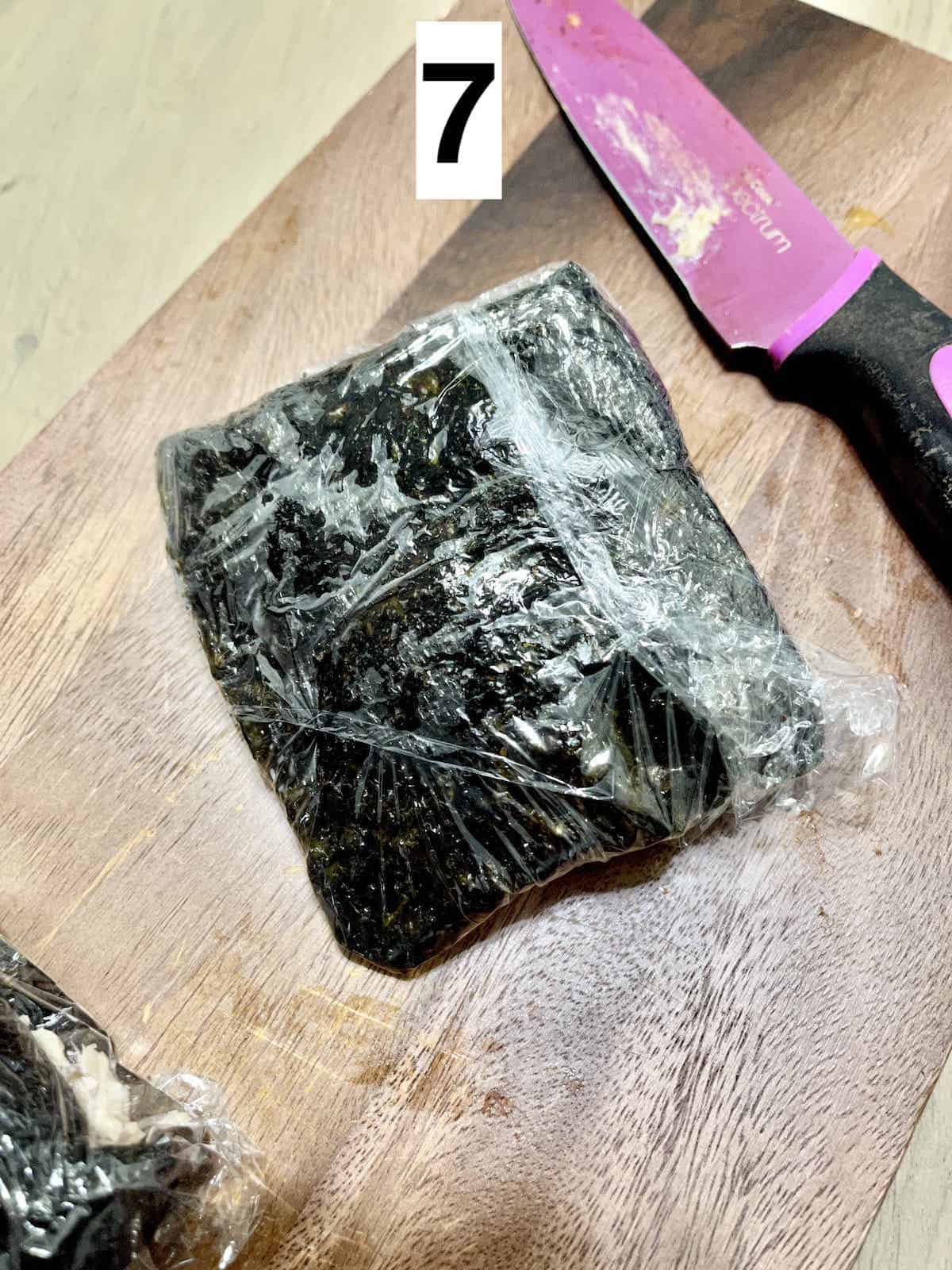 Korean seaweed sandwich wrapped in cling film next to a knife.