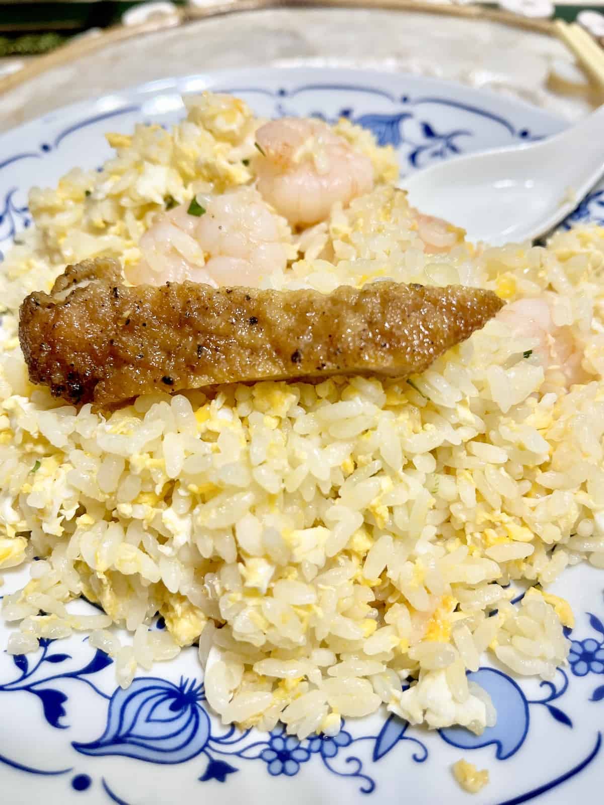 Close-up of short grain shrimp fried rice and a slice of pork.