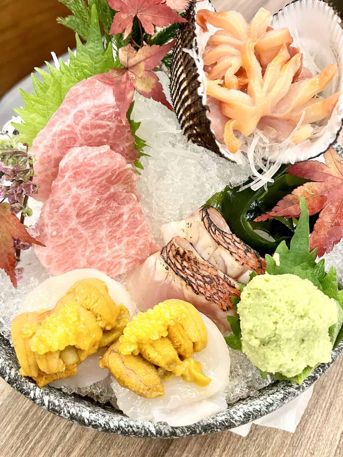 A platter of different types of Japanese sashimi and wasabi.