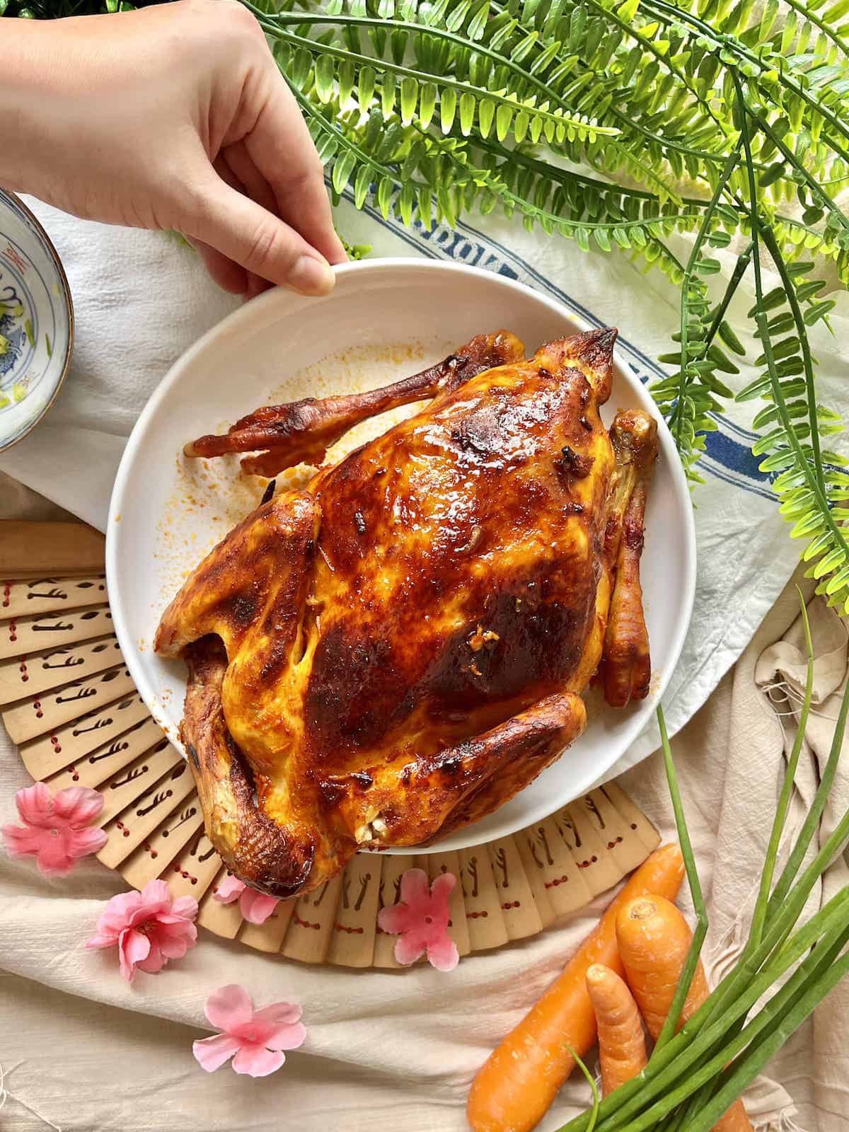 A Korean roast chicken glazed with gochujang sauce on a white plate.