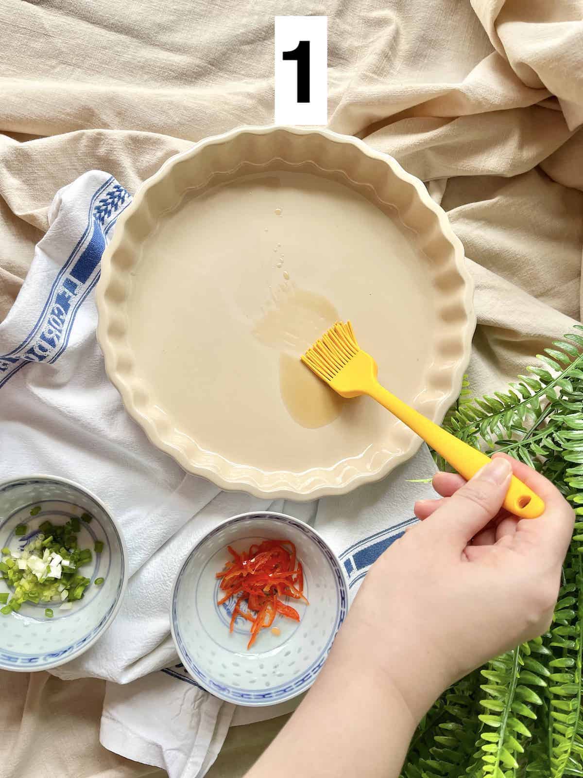 Brushing sesame oil onto a baking dish.