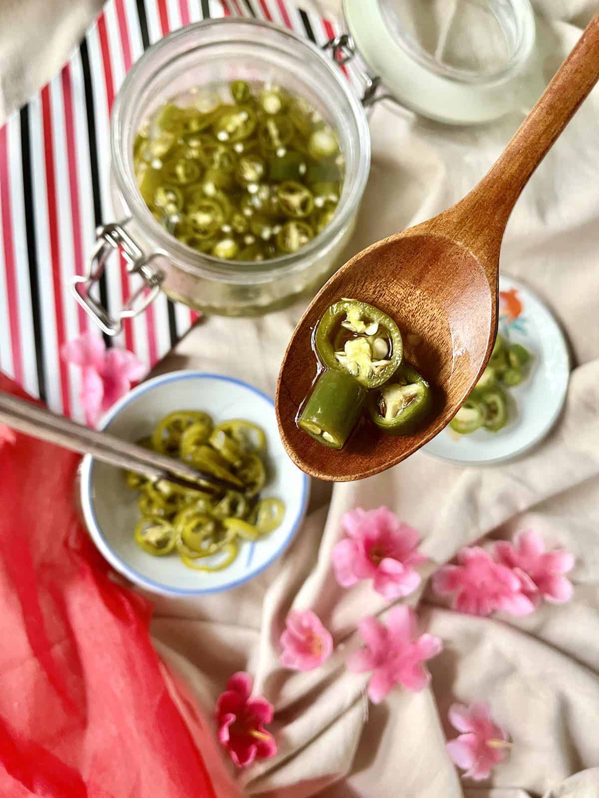 Sliced green chili pickles on a wooden spoon.