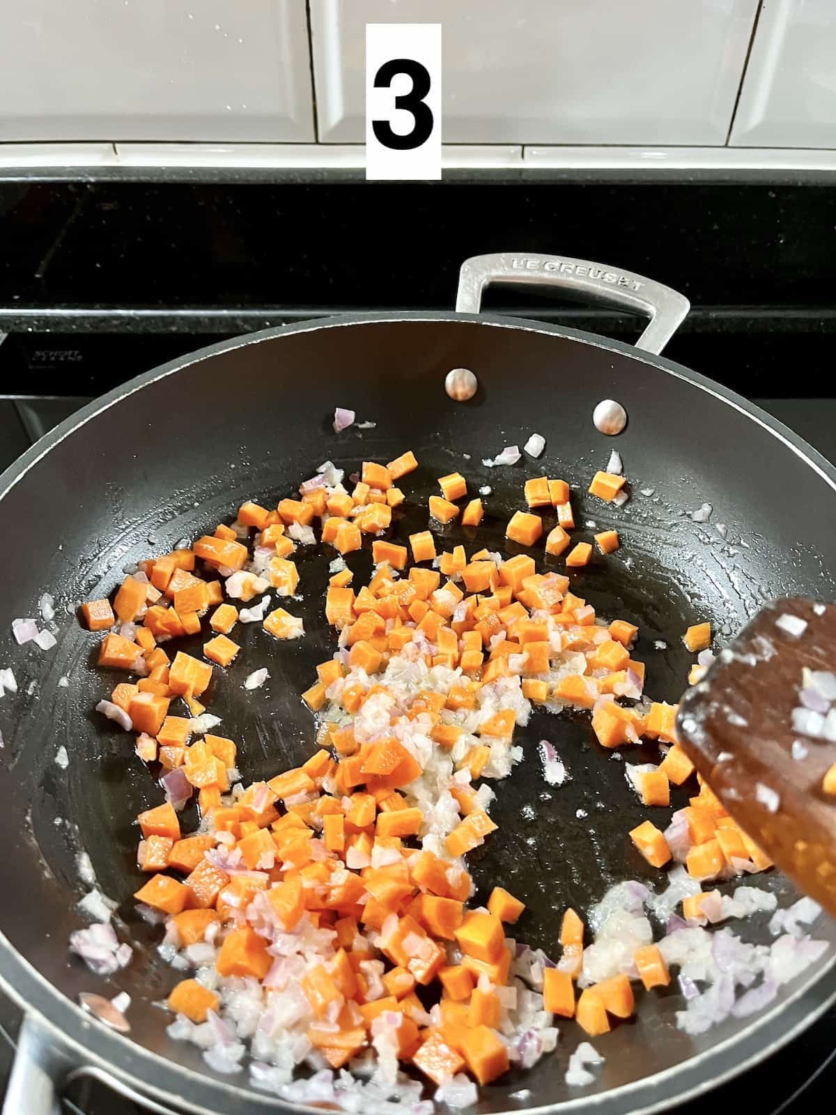 Stir frying carrots with onions and garlic in a pan.