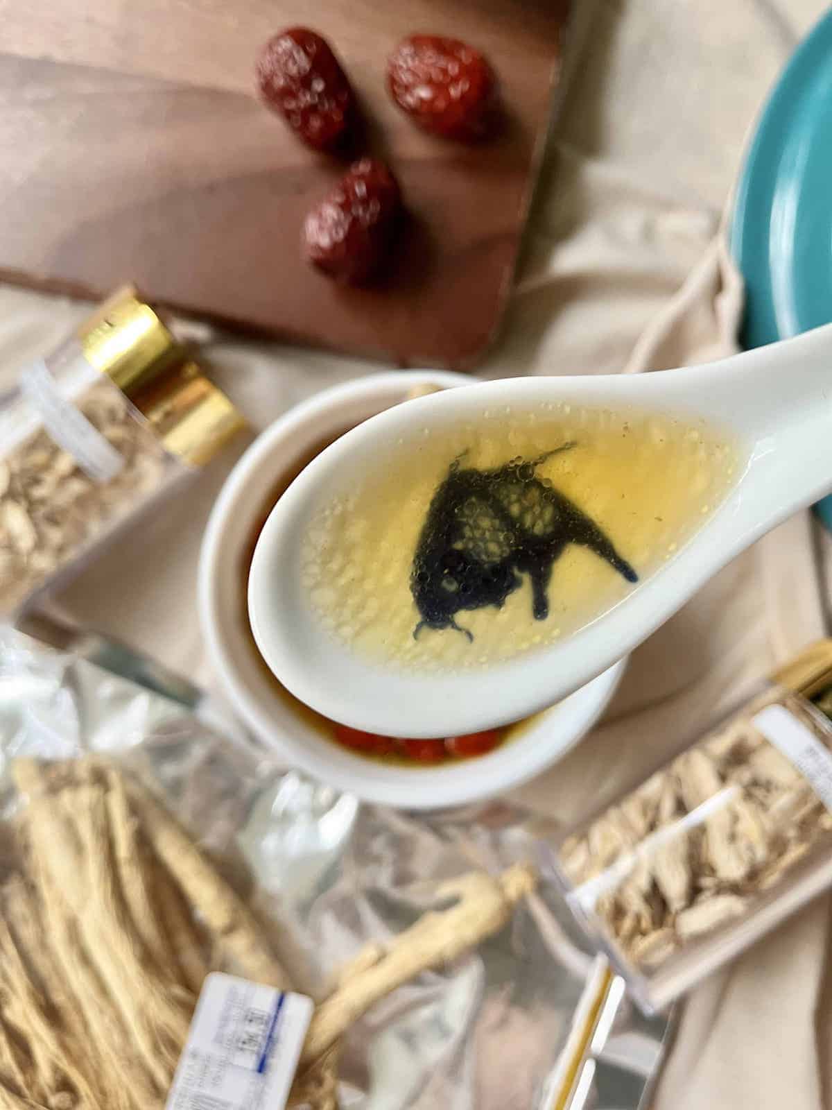 A spoonful of Chinese clear soup in a porcelain spoon.