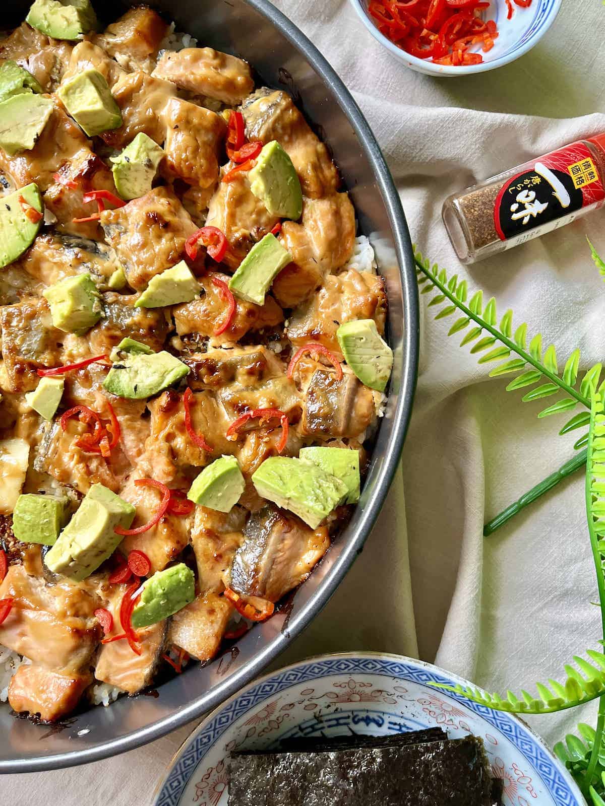 Avocado cubes and sliced chilies on top of baked salmon casserole.