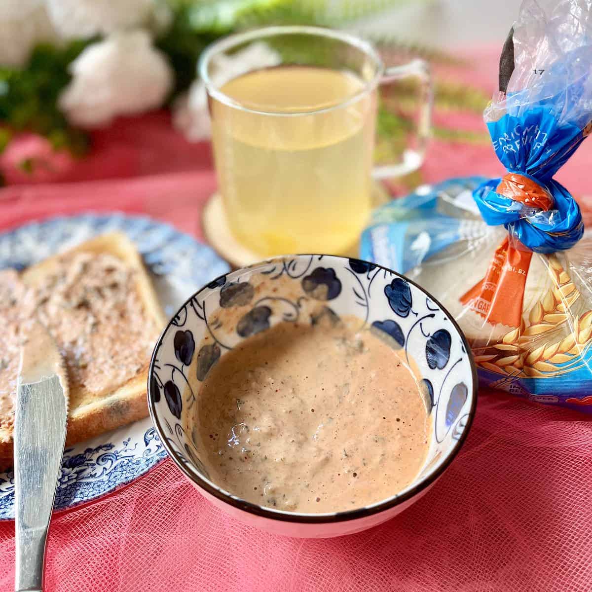 A bowl of kimchi mayo spread, with some slathered on a piece of toast to the side.