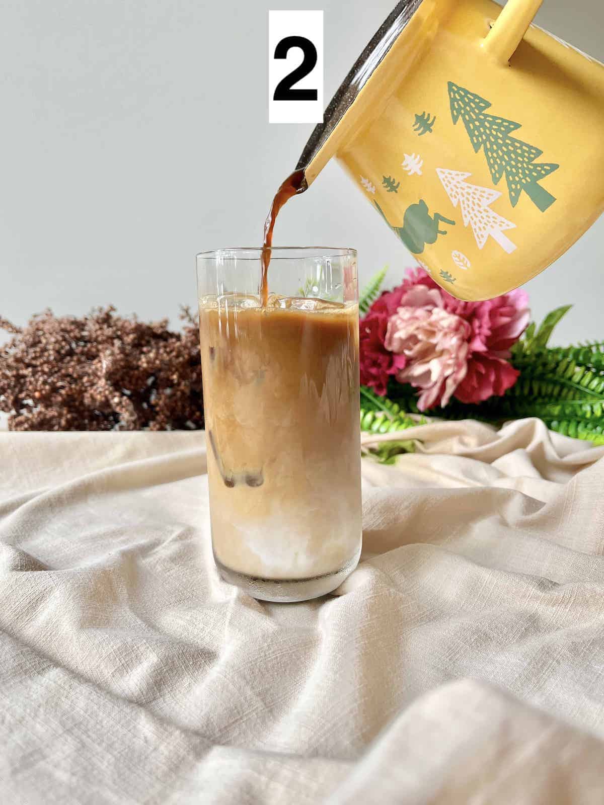 Pouring cold brew coffee into a glass of milk.