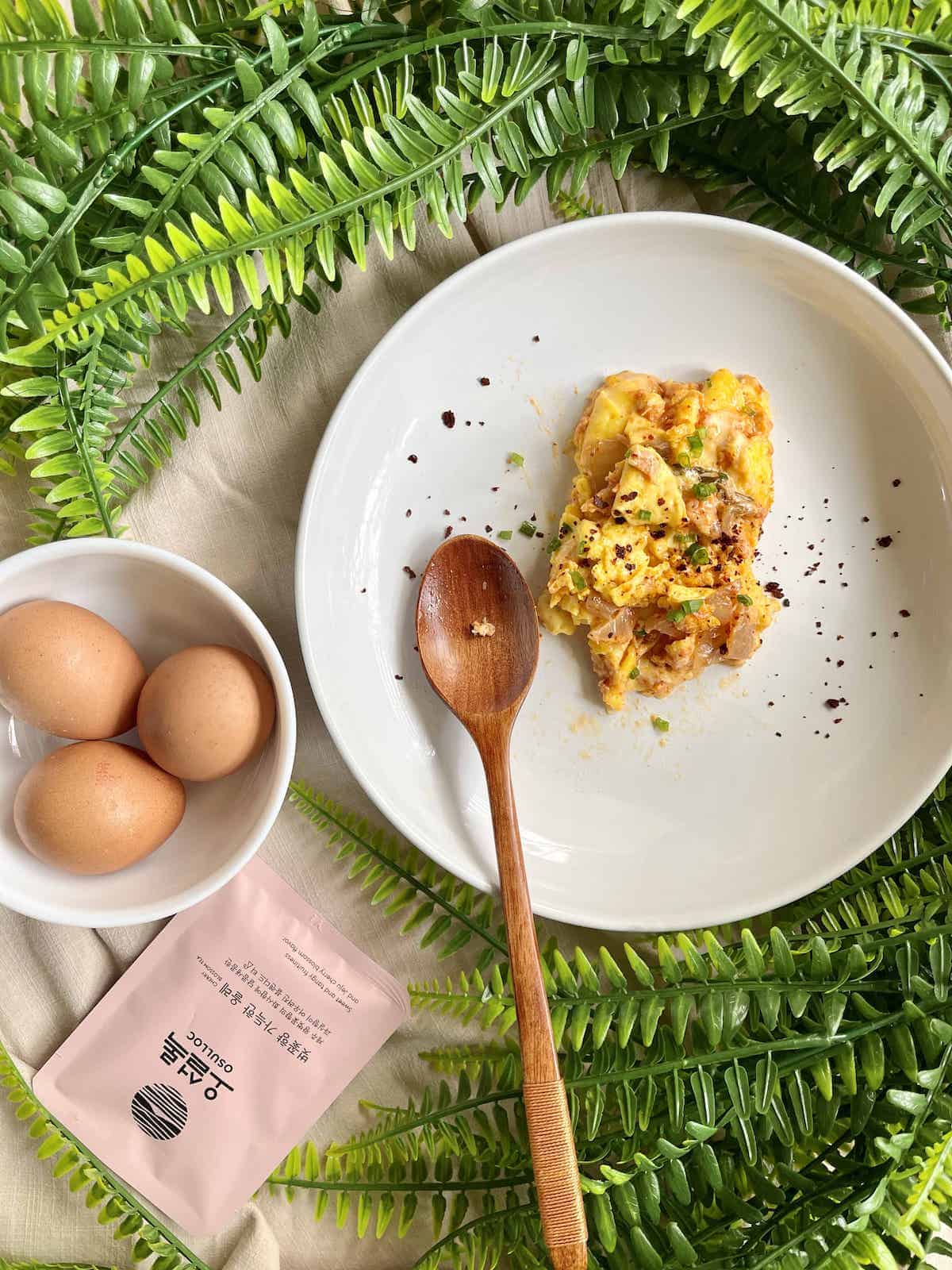 Overheat shot of scrambled eggs with cheese and kimchi on a white plate.