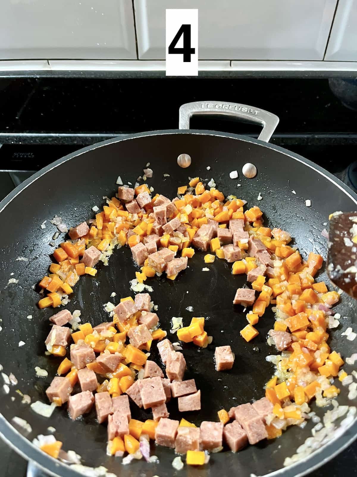 Mixing cubes of luncheon meat with the carrots, onions and garlic.