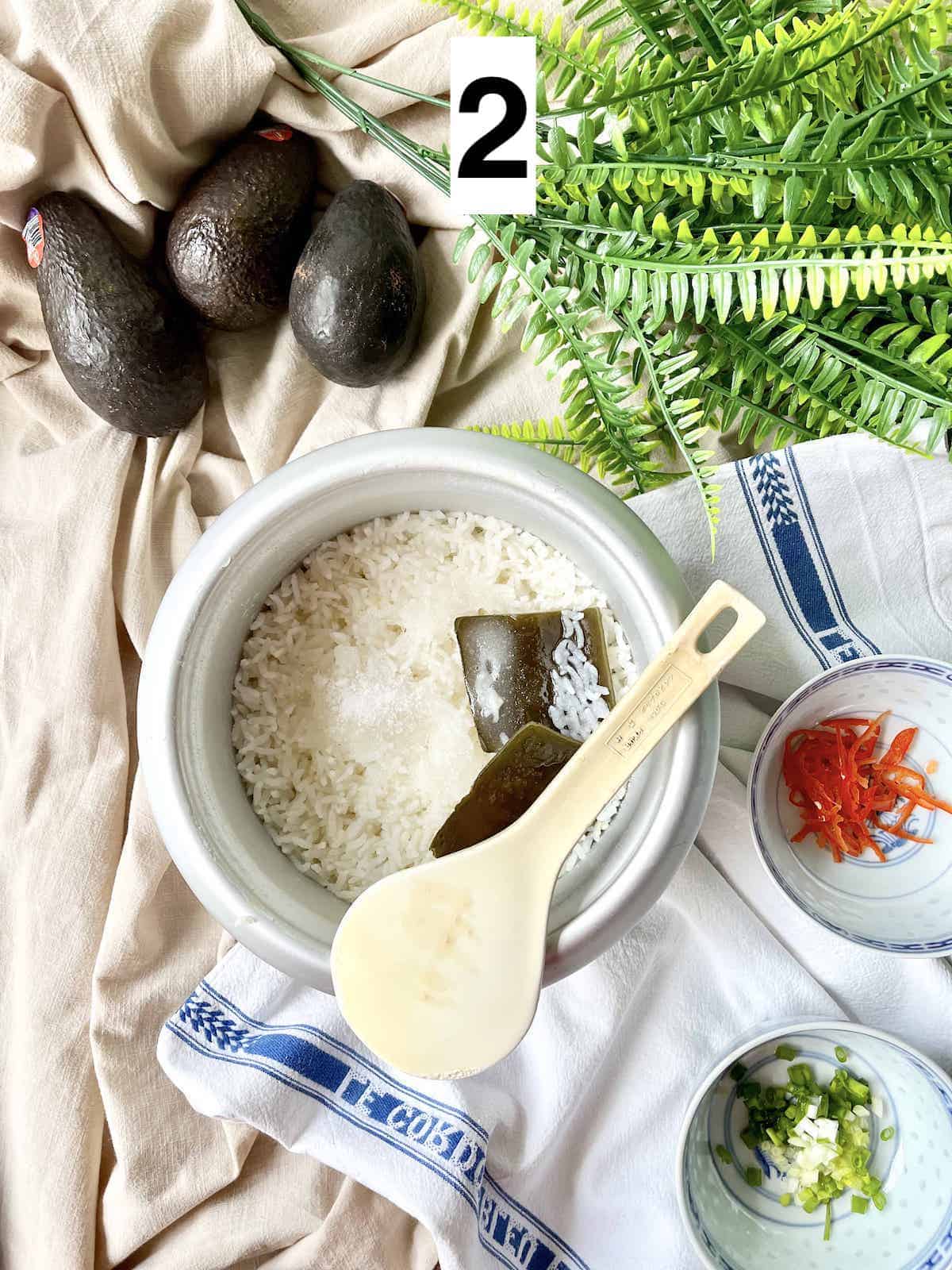 Sushi rice and kelp in a rice cooker pot.