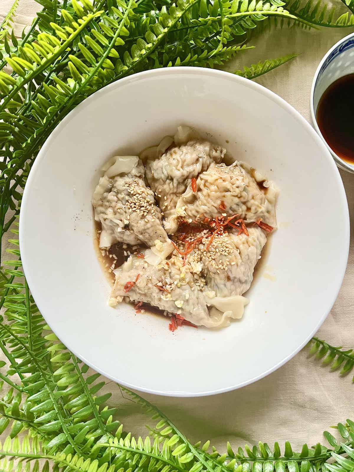 A bowl of Chinese dumplings in a spicy soy sauce.