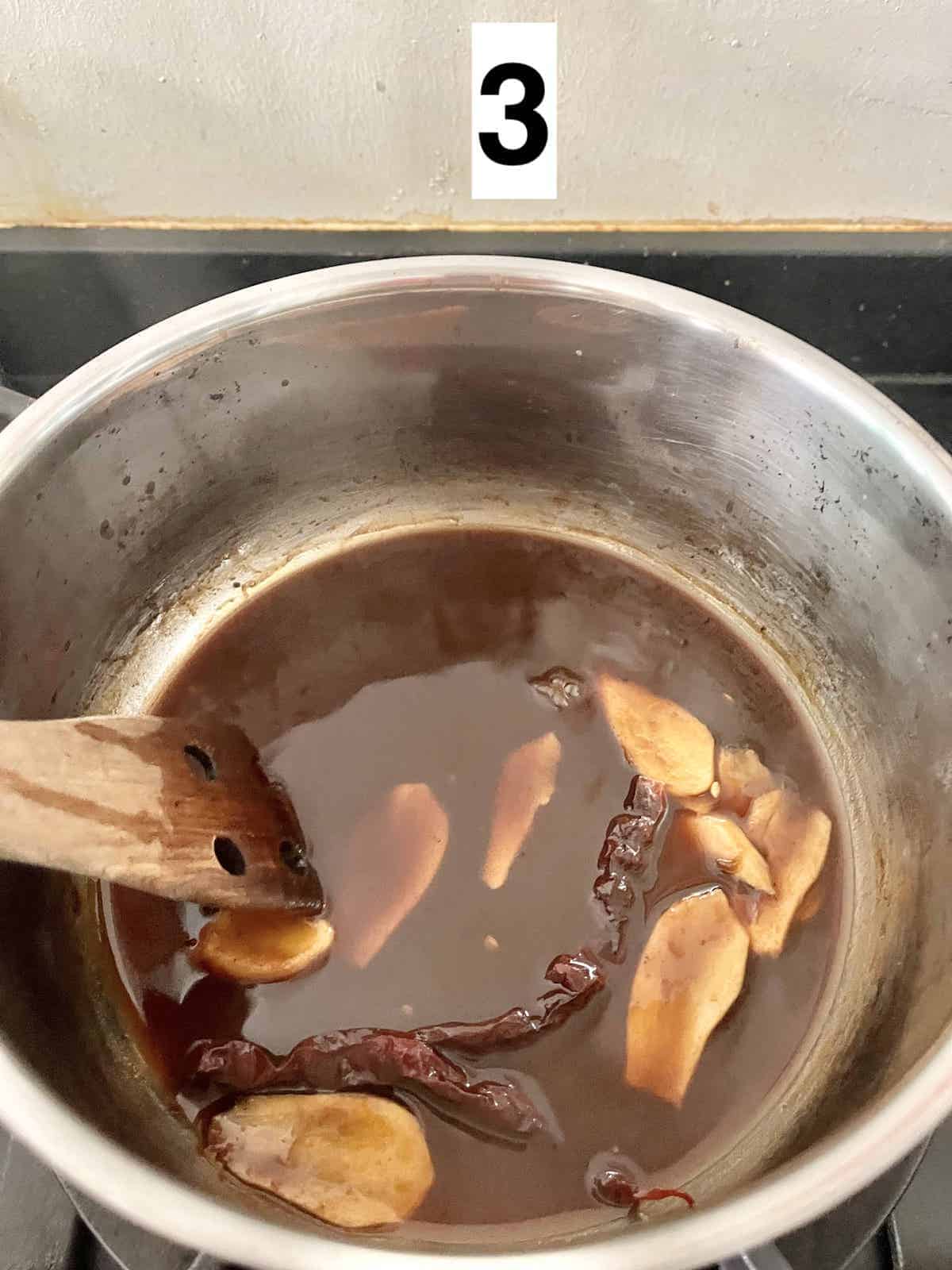 Boiling tamarind water and ginger and chilies.