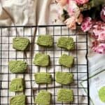 12 bright green matcha cookies on a wire rack.