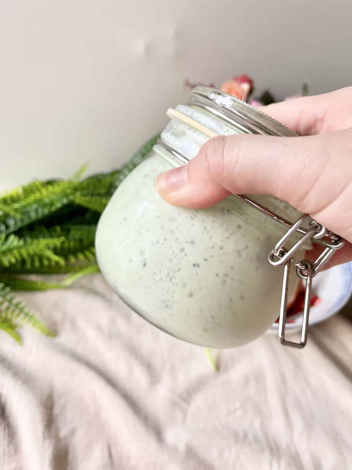 Shaking matcha powder and milk in a mason jar.