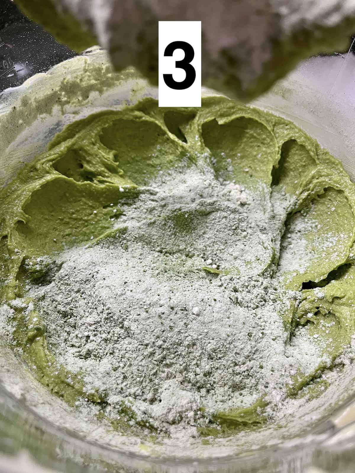 Adding green tea powder and flour to the creamed butter sugar mixture.