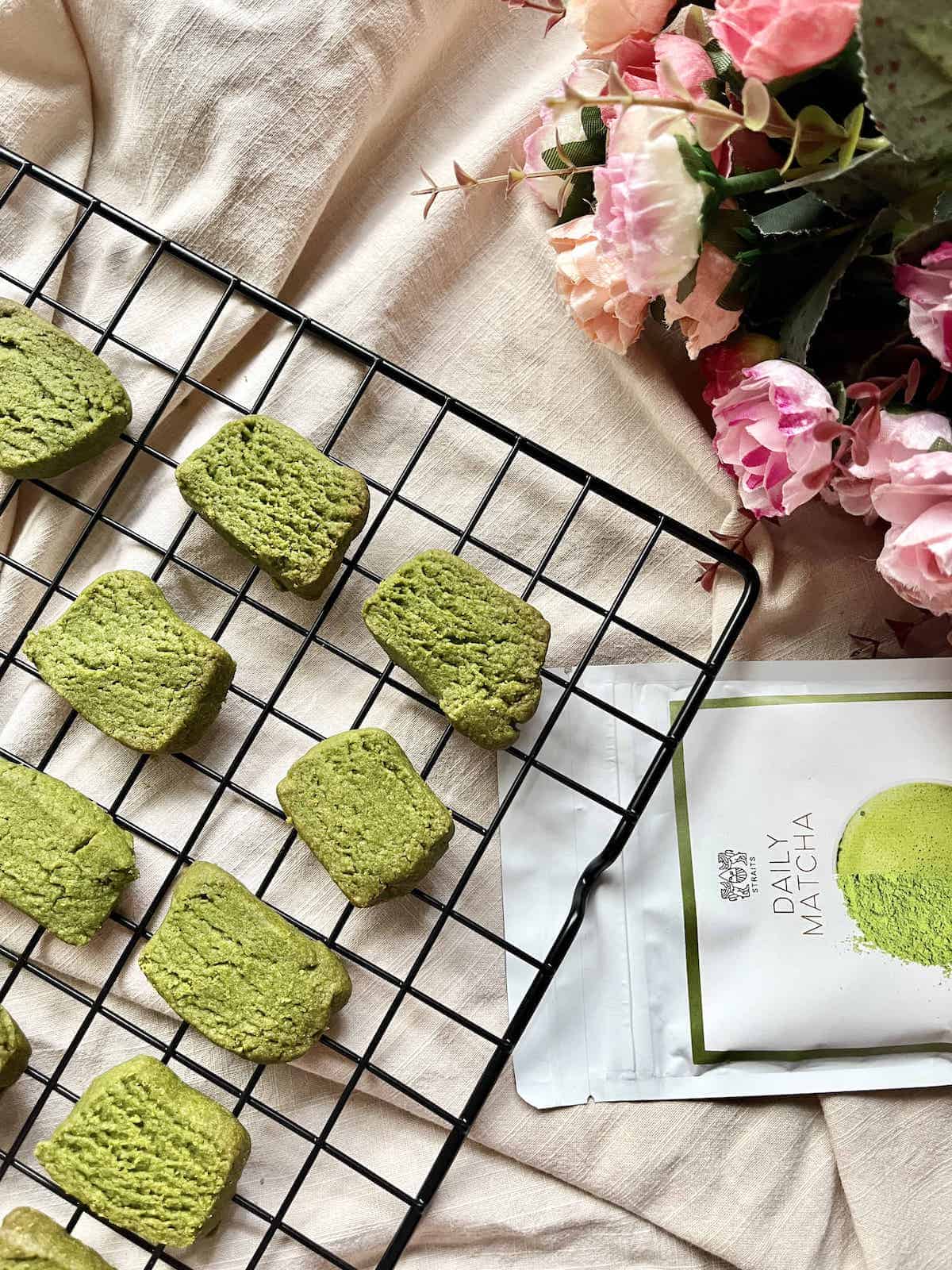 Homemade matcha cookies on a black cooling tray.