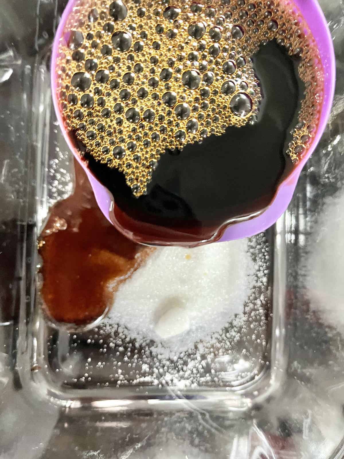 Pouring soy sauce onto white sugar and hot water.