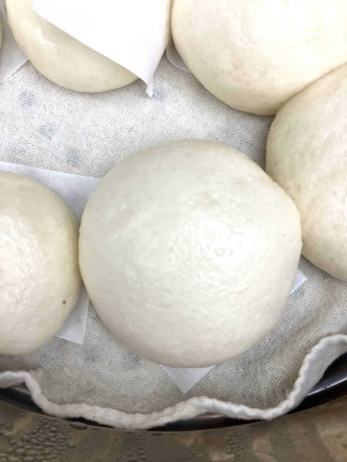 5 homemade Chinese bao buns in a bamboo steamer.