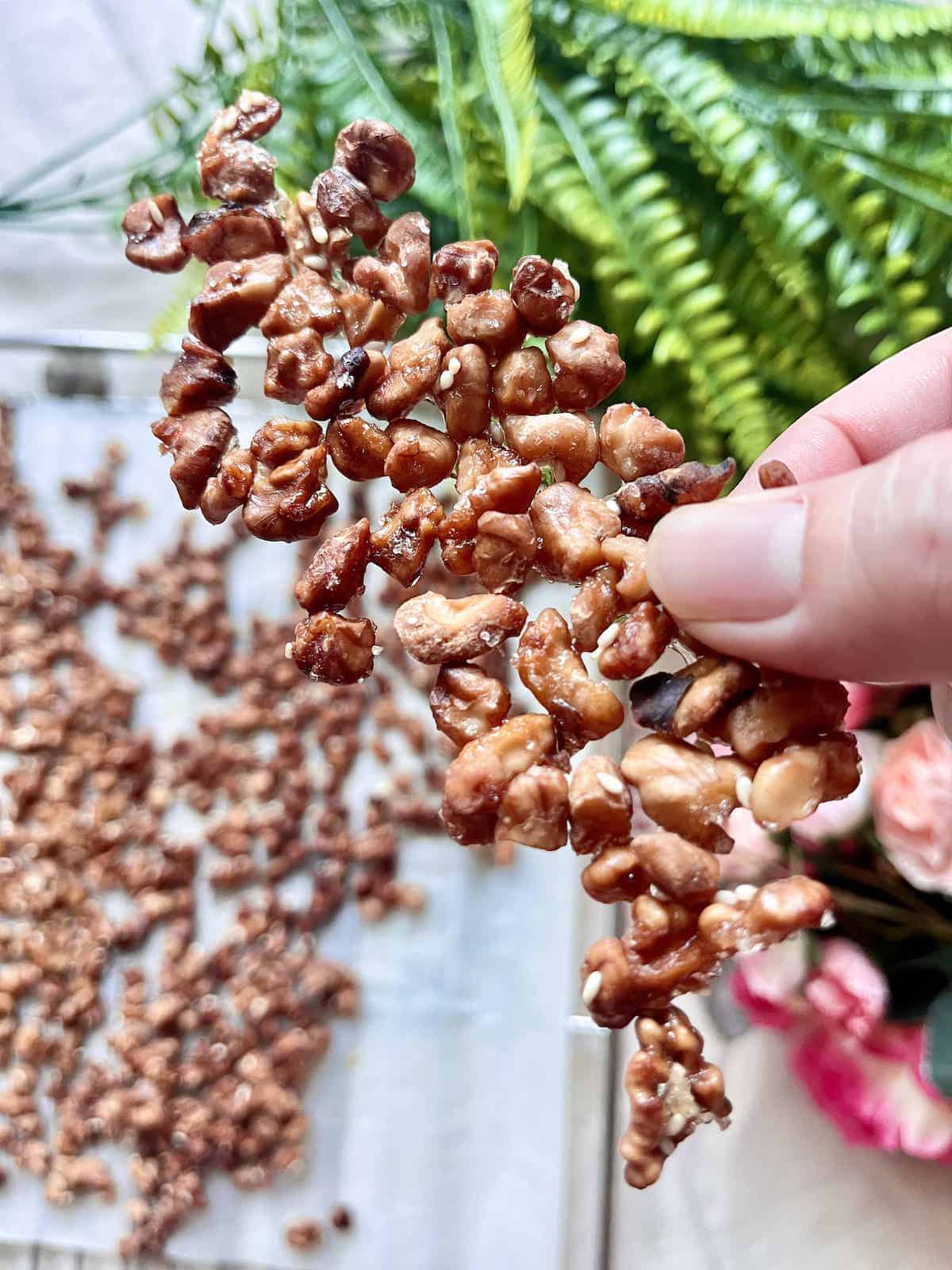 Holding up a big pieces of Chinese walnut candied with sesame seeds.