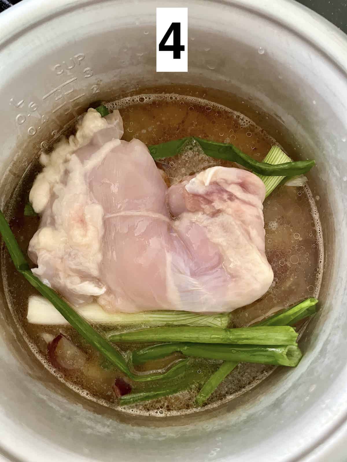 Chicken, rice, and aromatics in a rice cooker.