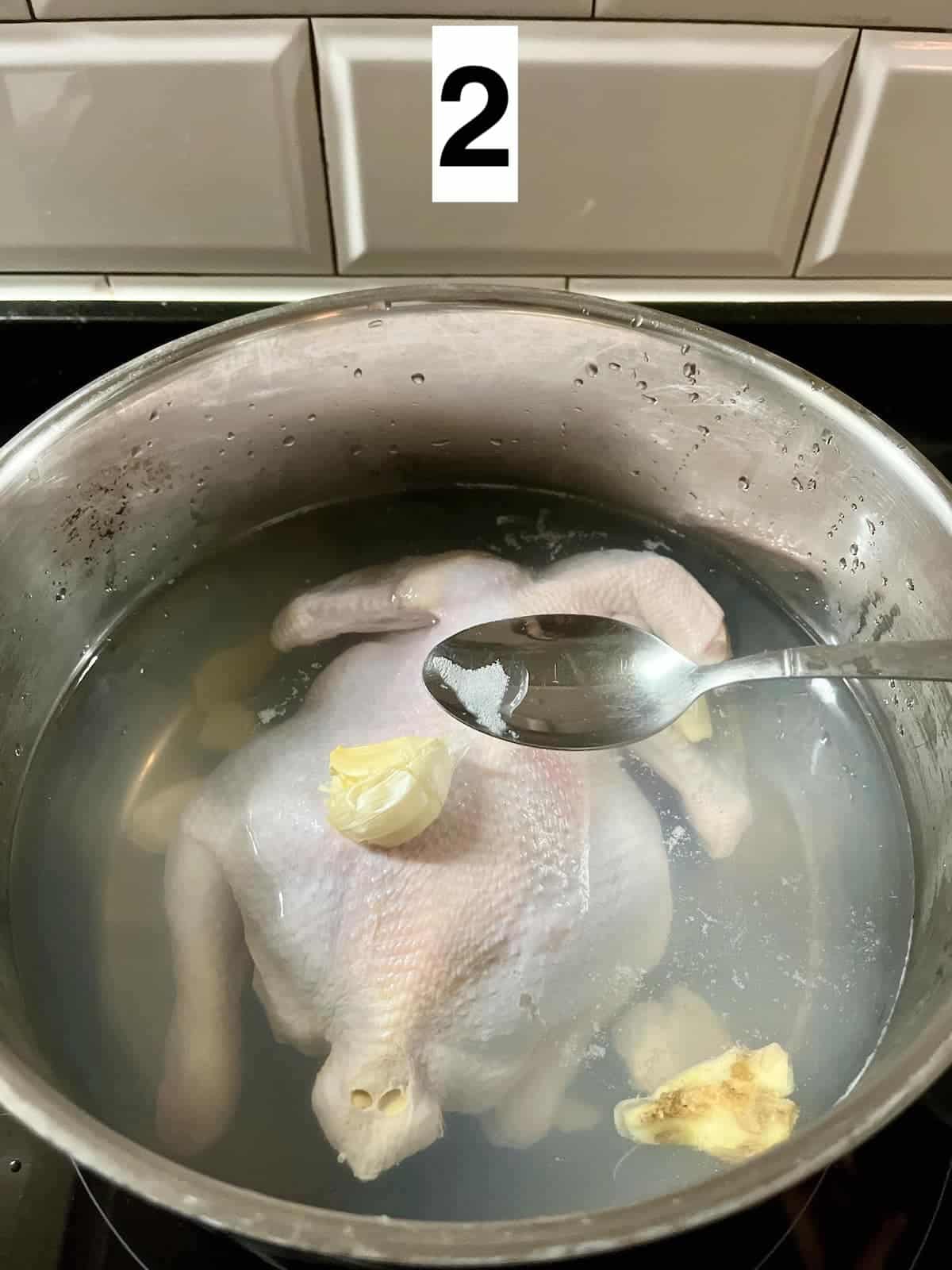 Removing white foam from the pot of chicken stock.