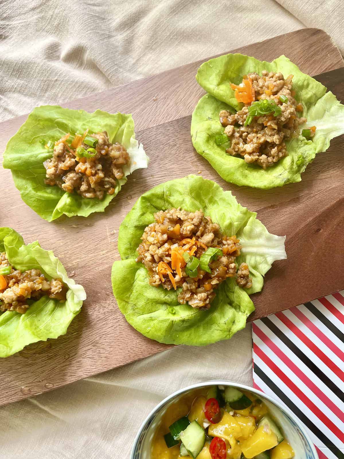 Homemade Chinese pork lettuce wraps on a wooden board.