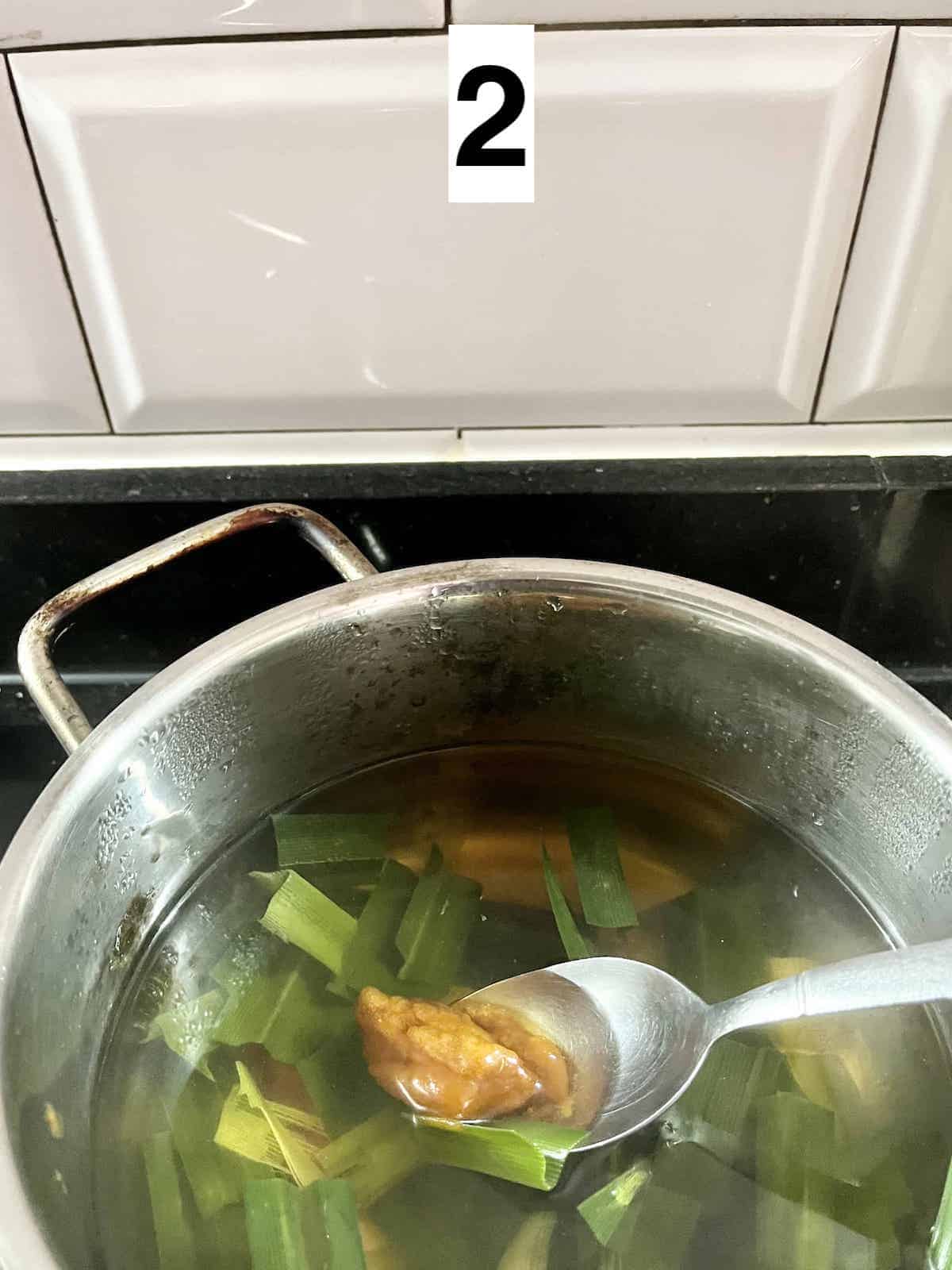 Adding palm sugar to boiling pandan tea.