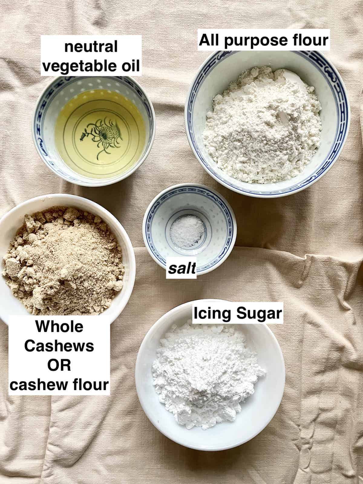 5 ingredients for Cashew Cookies on a linen cloth.
