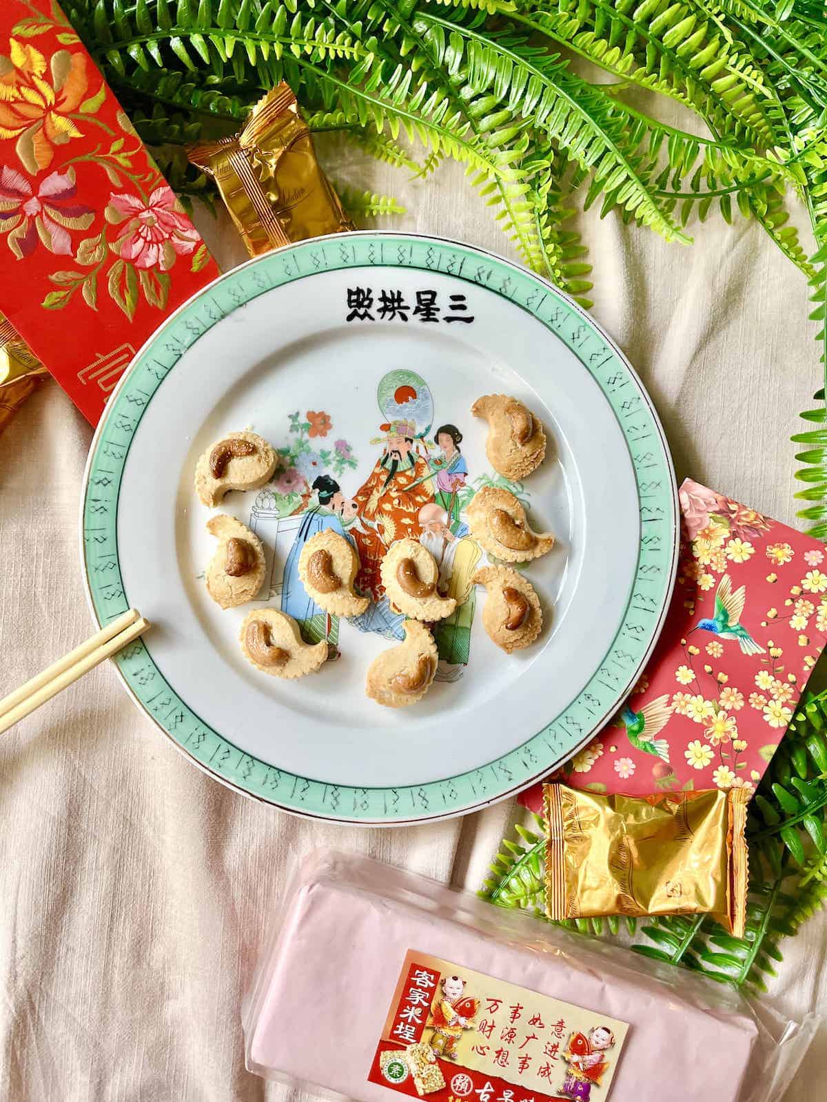 A plate of Chinese Cashew Cookies with Chinese New Year decorations around.