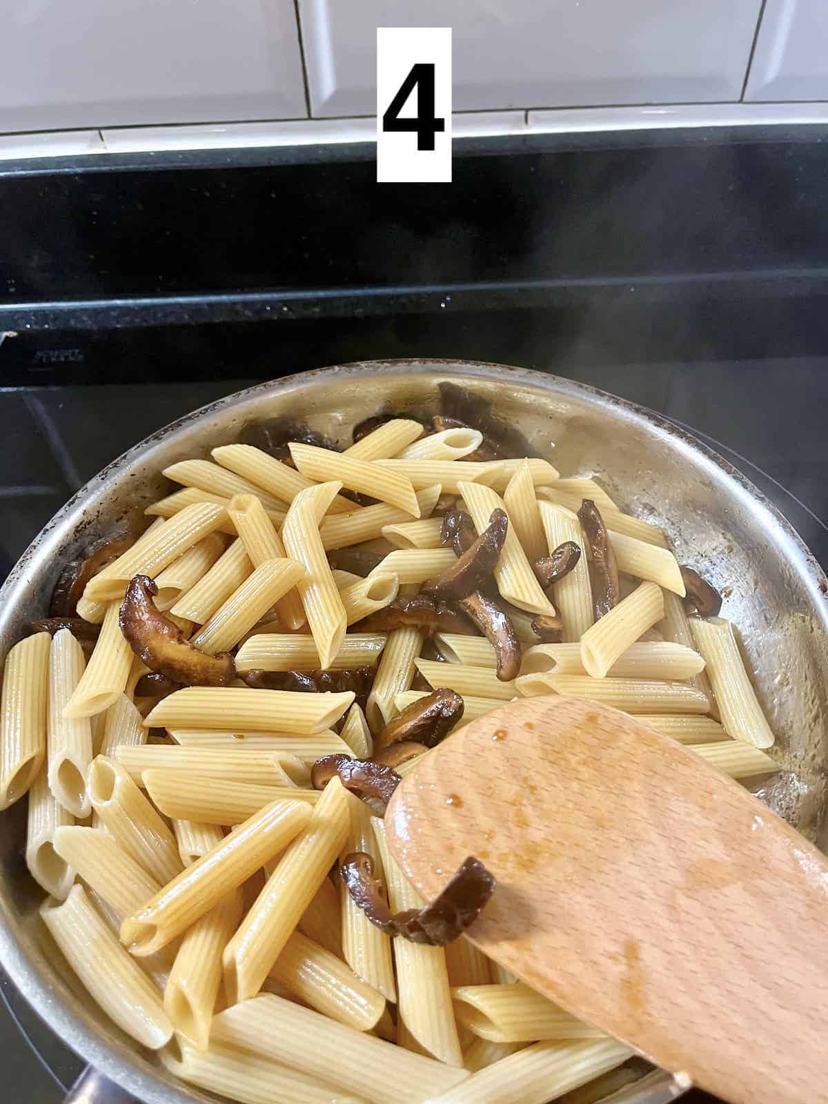 Sauteeing penne pasta in a pan.