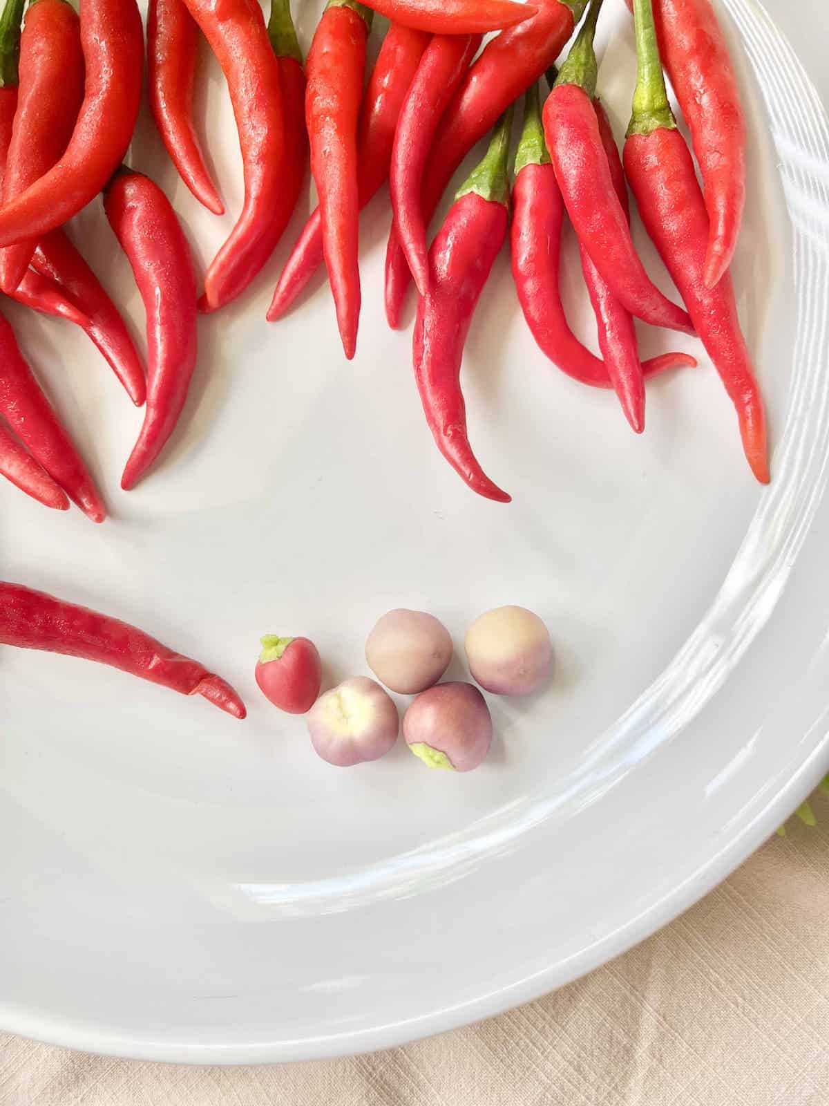 Some fresh purple chilies next to fresh Thai chilies.