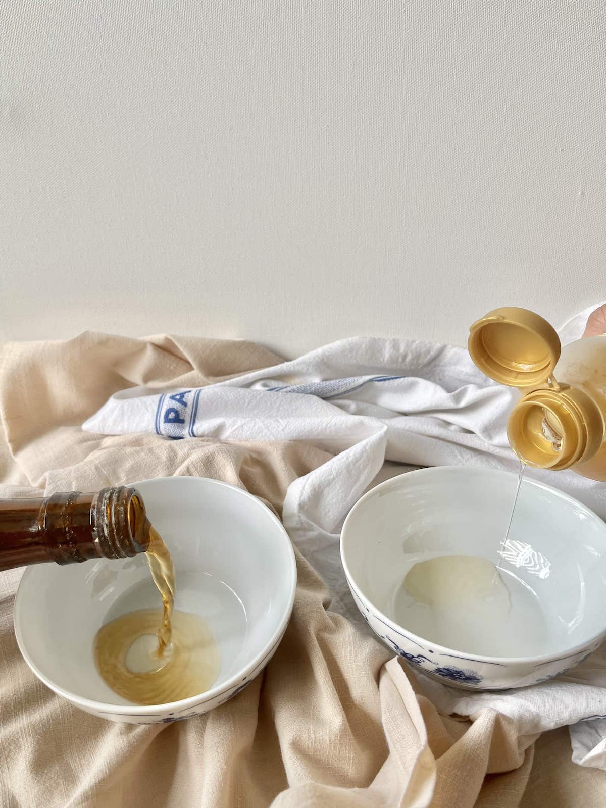 Pouring sake into a bowl next to pouring mirin into a bowl.