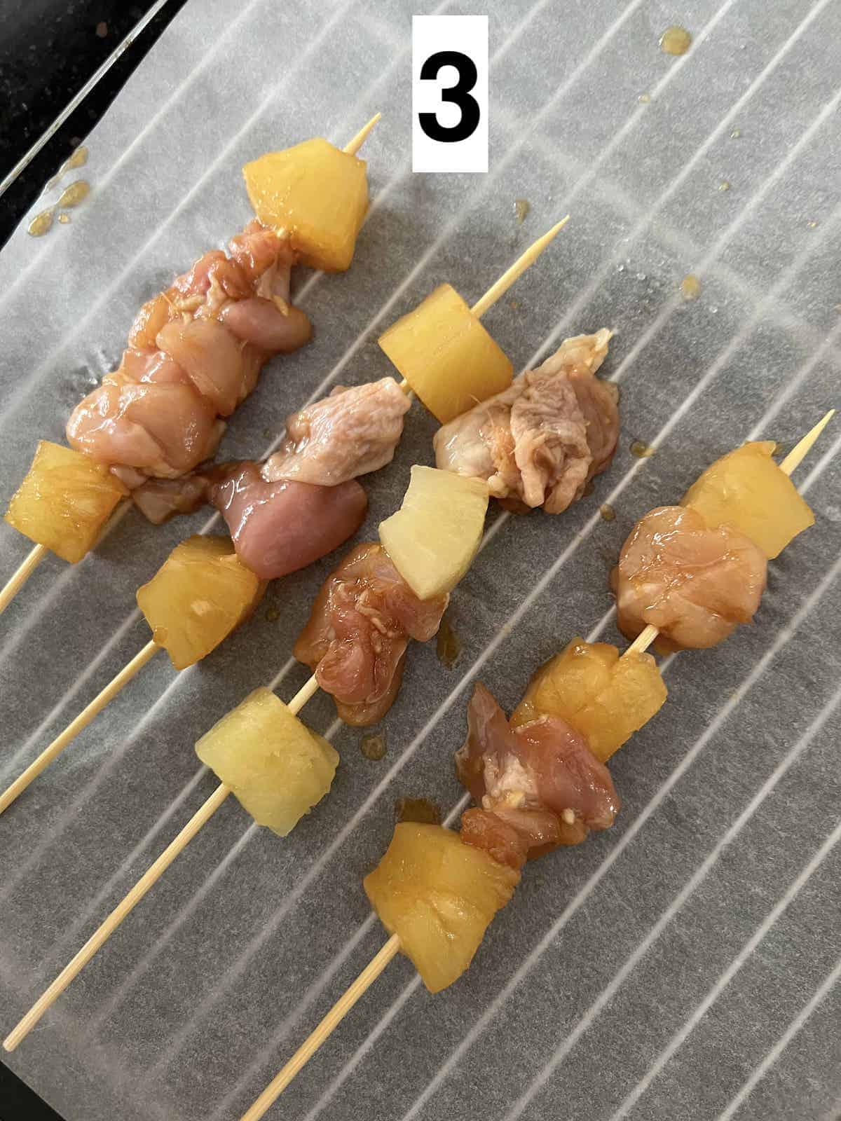Skewered chicken and pineapple on wooden sticks.