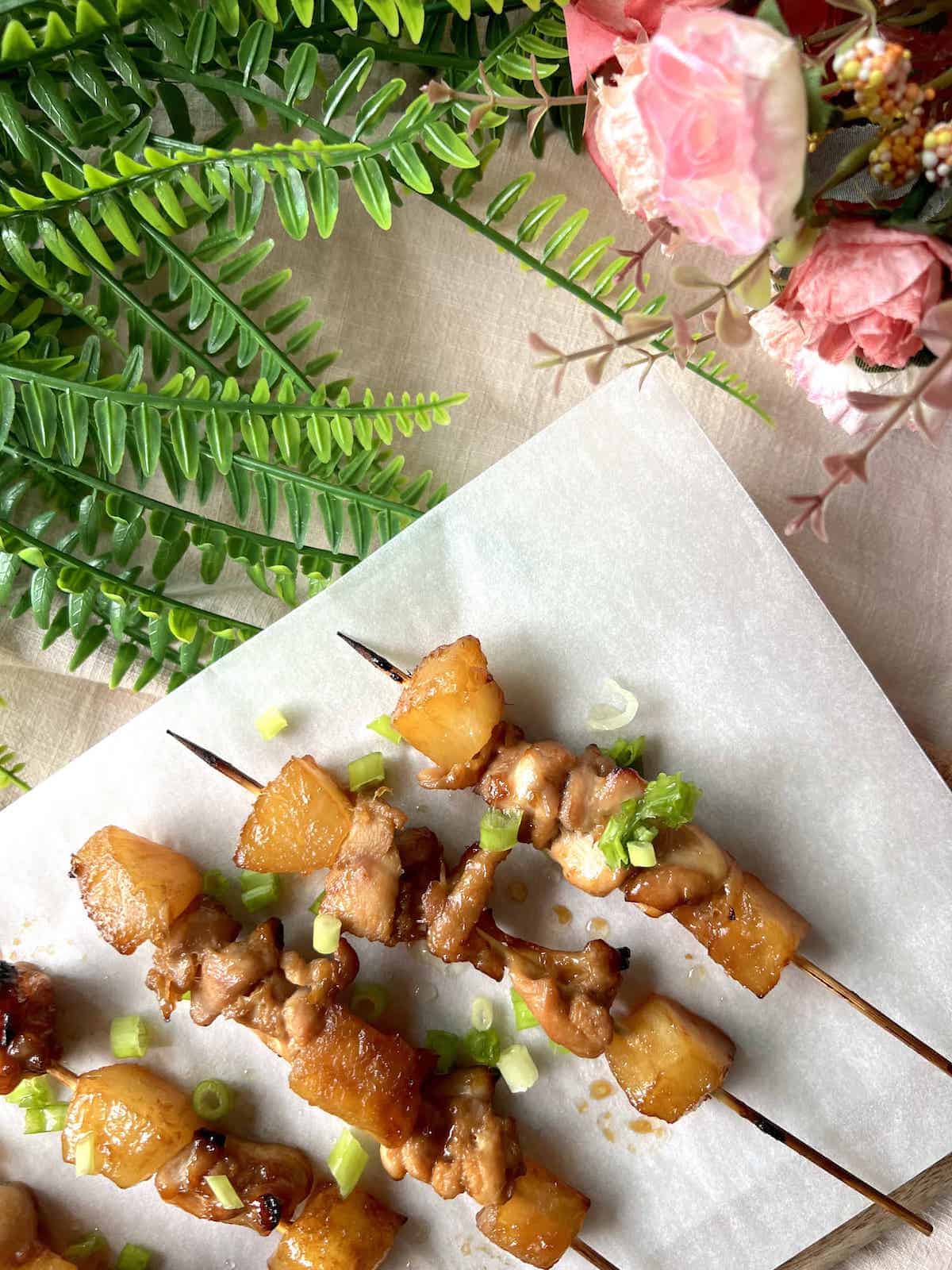 4 chicken teriyaki with pineapple skewers on parchment paper.