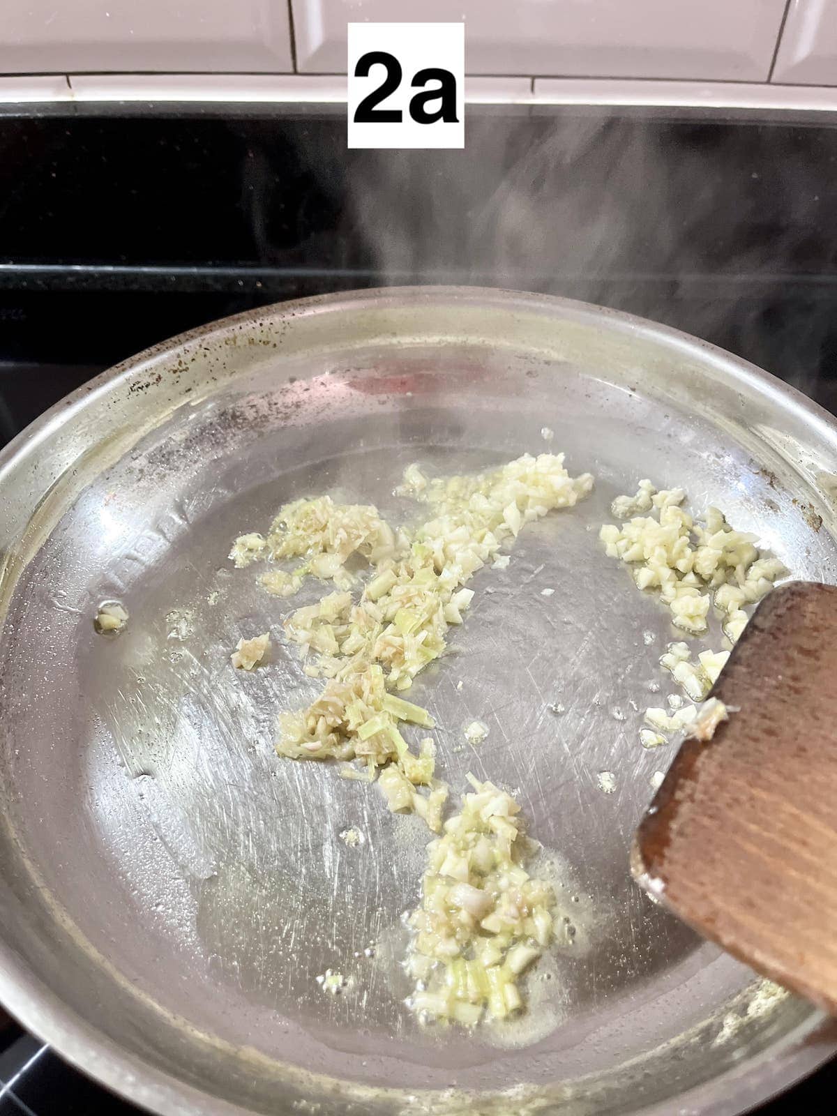 Minced lemongrass and garlic being stir-fried in oil in a pan.