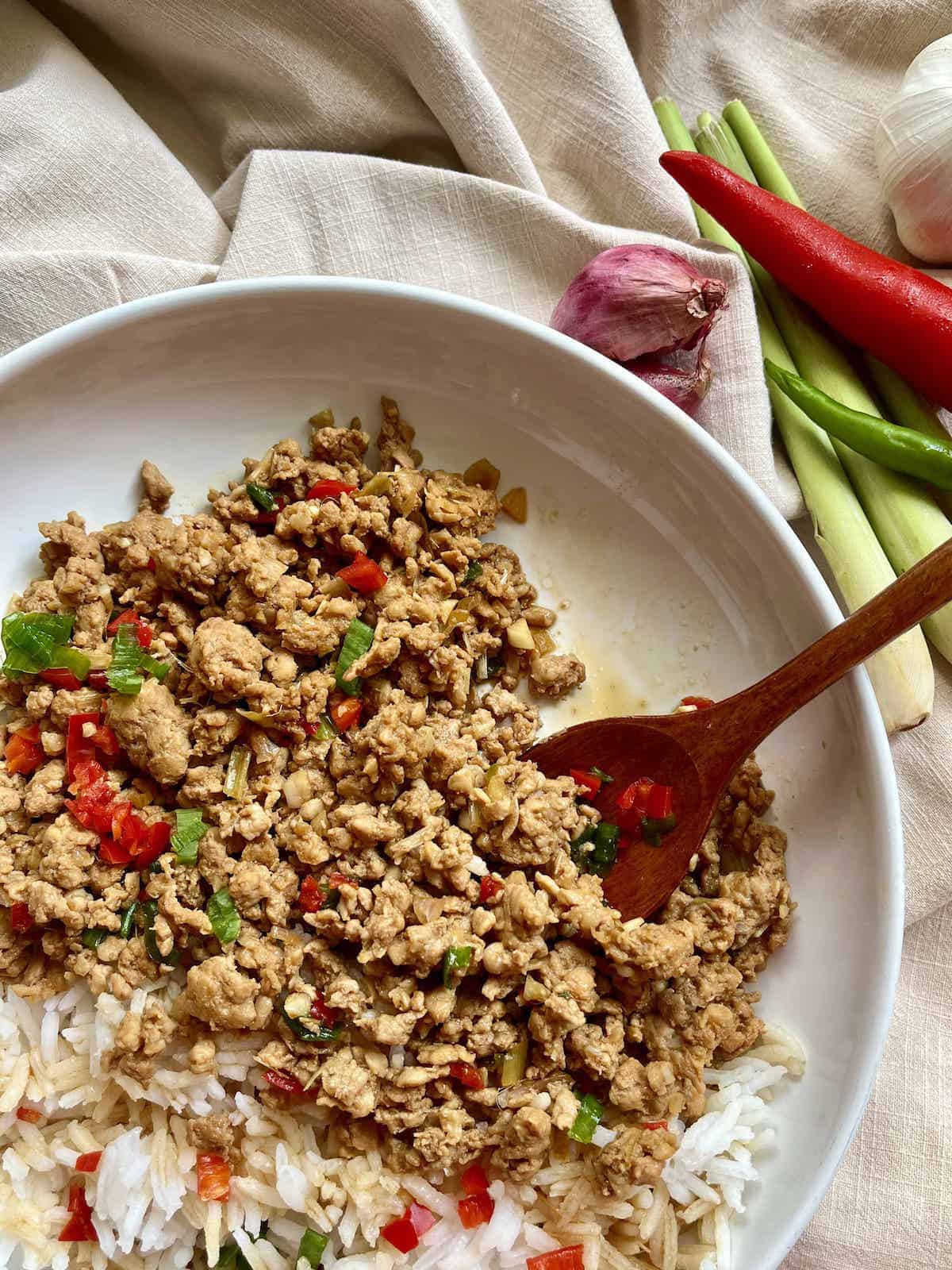 Stir-fried ground chicken with lemongrass, chicli, and white rice on a white plate.