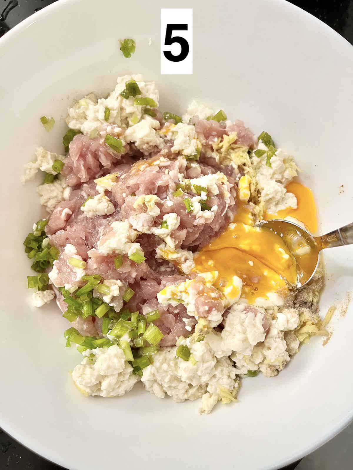 Mixing minced chicken, firm tofu, egg, and seasoning in a bowl.