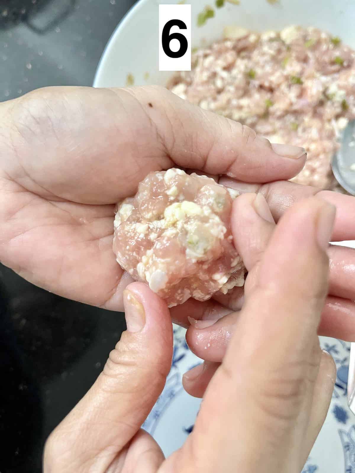 2 hands forming a chicken tofu meatball.
