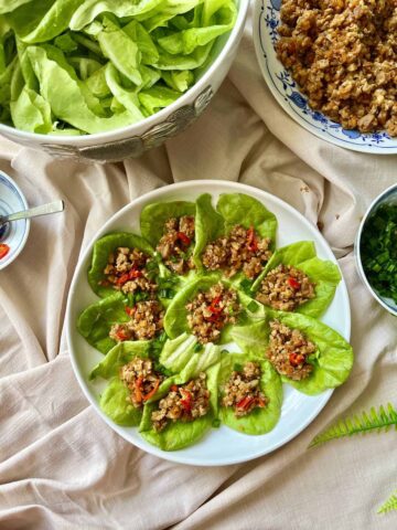 Many chicken lettuce wraps on a white plate.