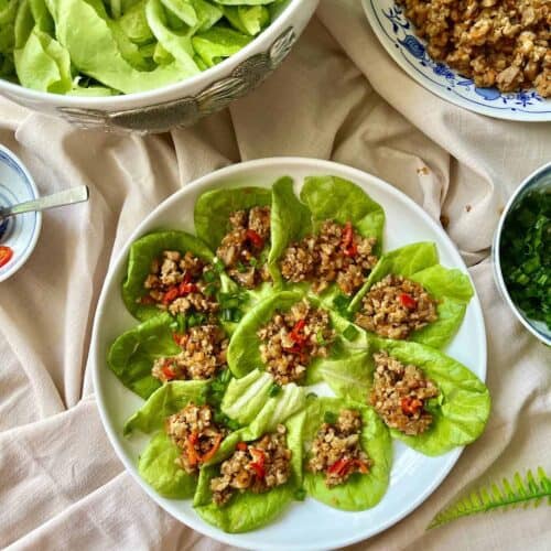 Many chicken lettuce wraps on a white plate.