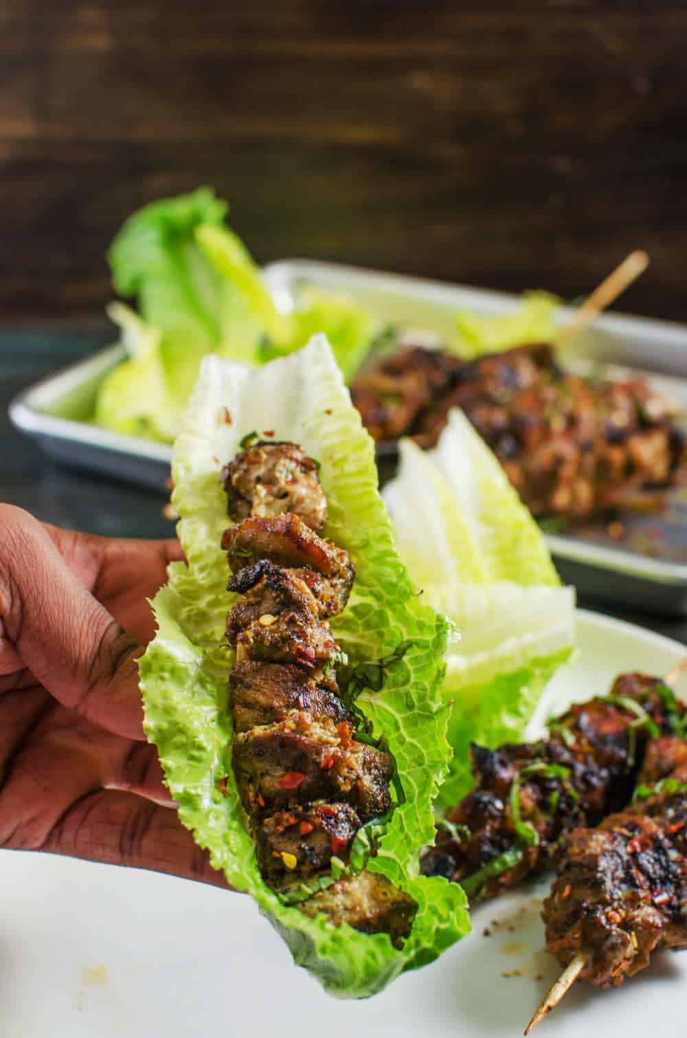 A Thai chicken skewer in a lettuce leaf.
