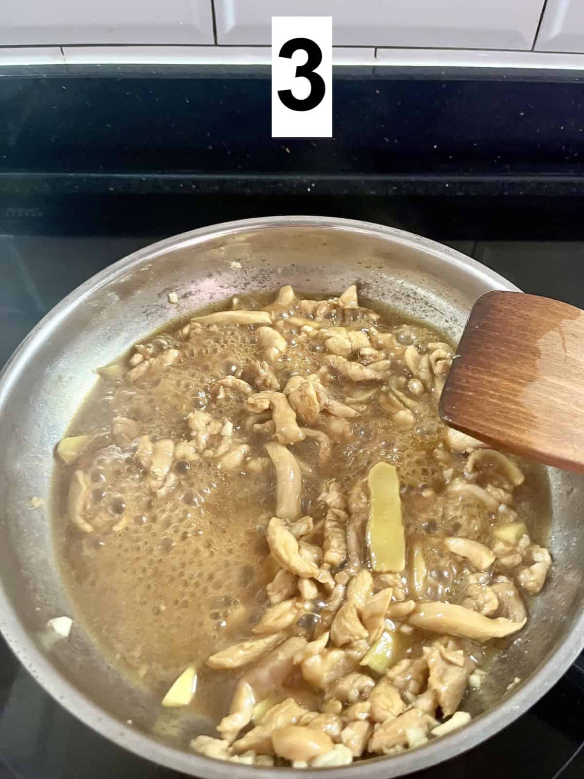 Cooked chicken in teriyaki sauce in a stainless steel pan.
