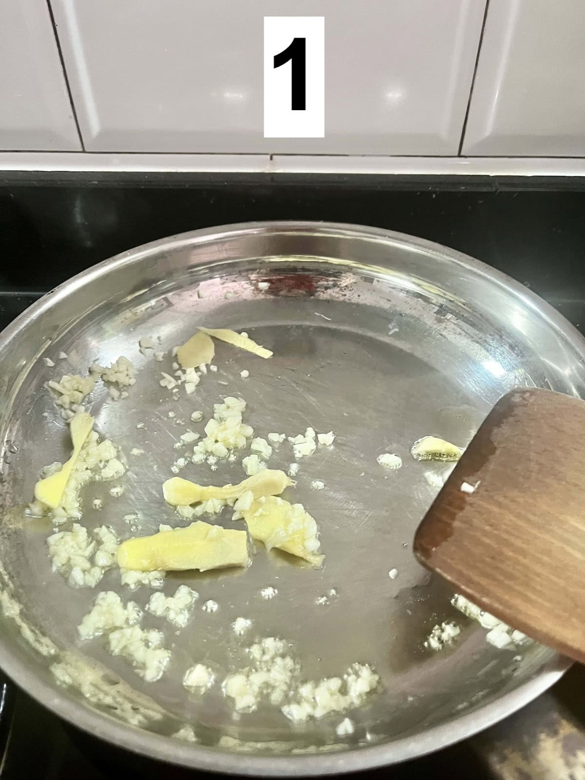 Stir-frying ginger and garlic in a stainless steel pan.